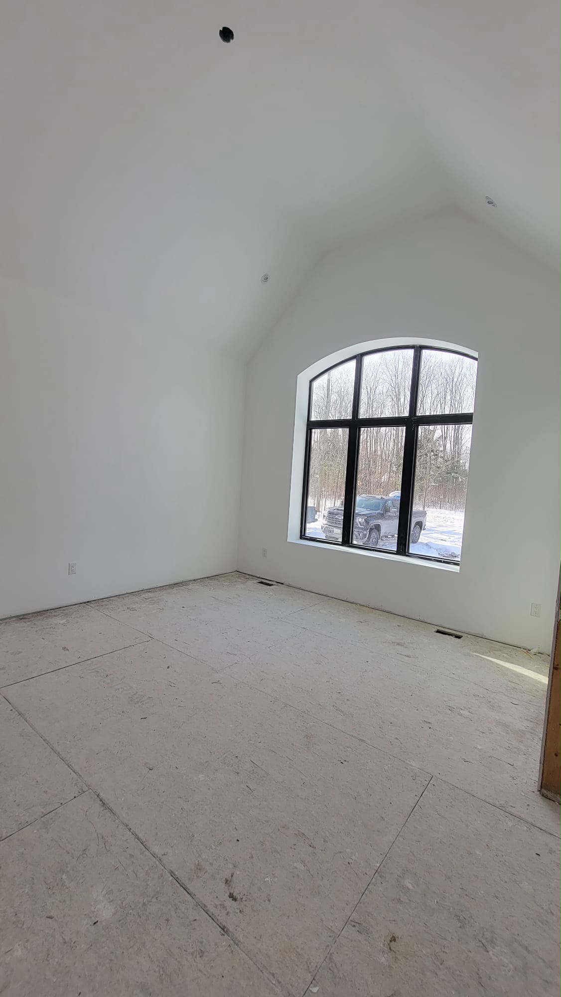 Residential great room completed — bright white walls and dramatic arched window