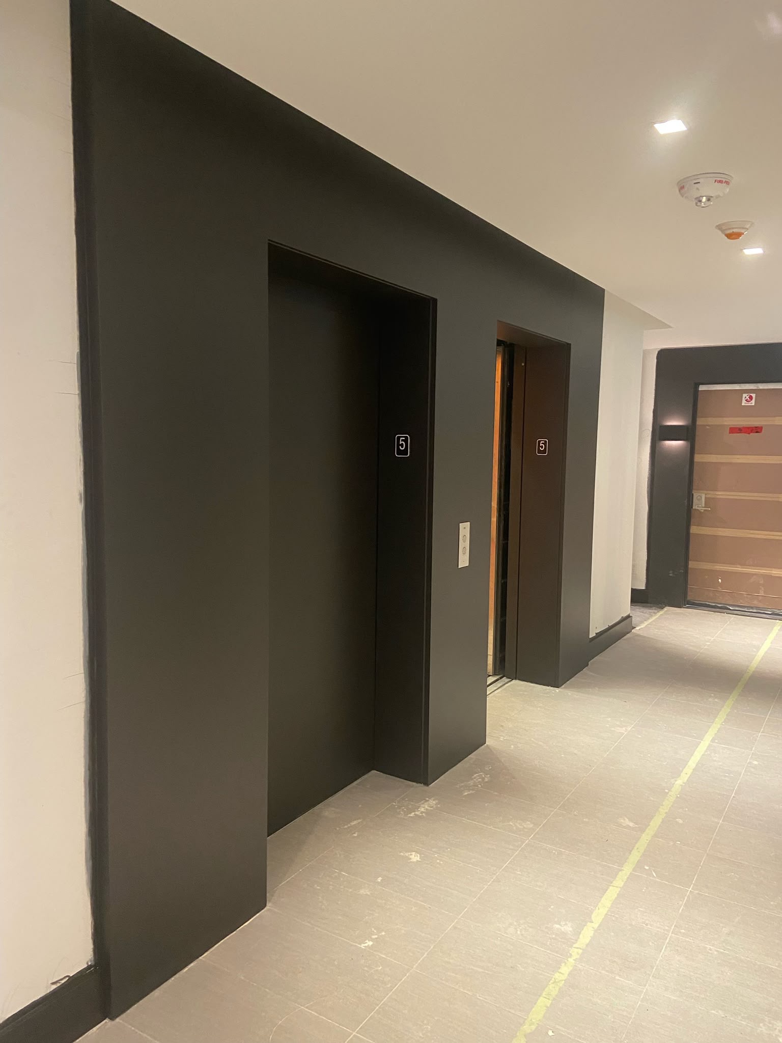 Elevator lobby after painting — bold black-painted surround with high-contrast finish
