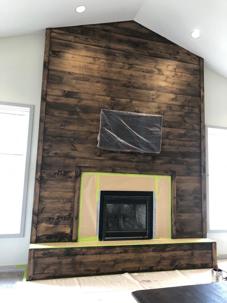 Fireplace shiplap feature wall after staining — rich dark walnut finish with fireplace surround