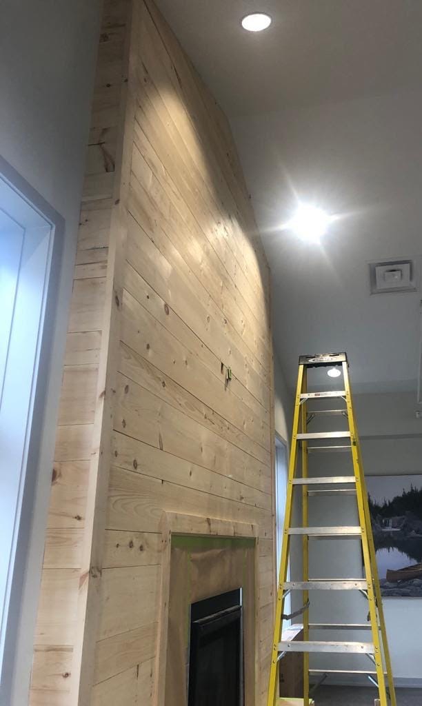 Fireplace shiplap feature wall before staining — raw natural pine boards