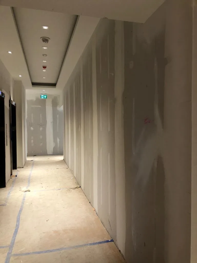 Drywall installation and preparation in a commercial hallway before painting in Ottawa