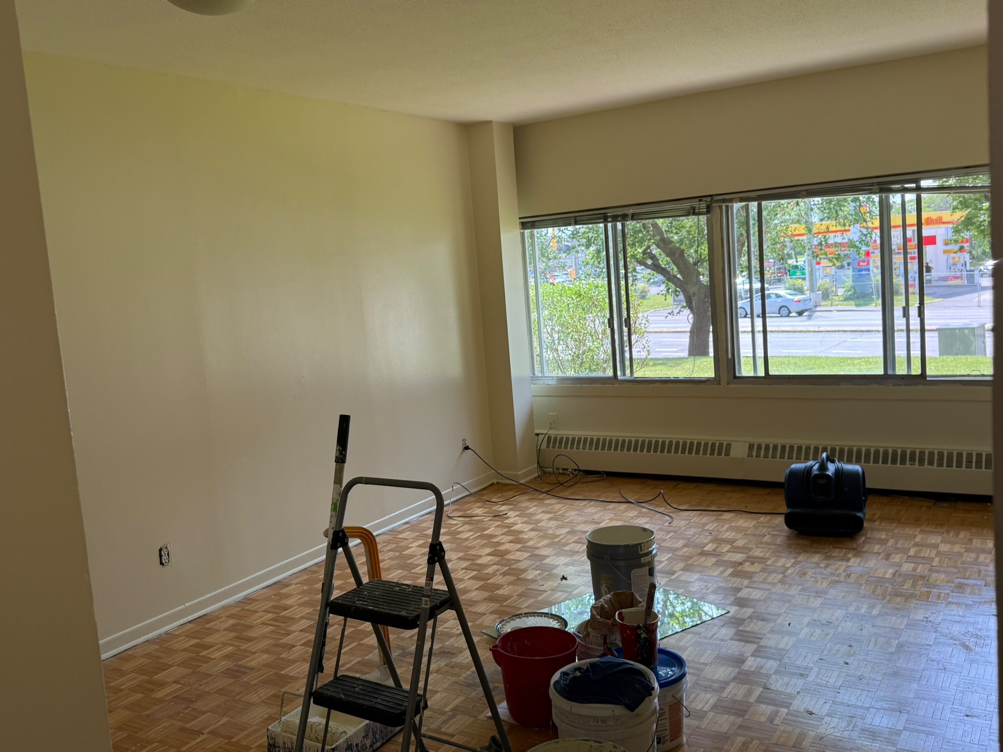 Apartment living room mid-painting — white covering old coloured walls