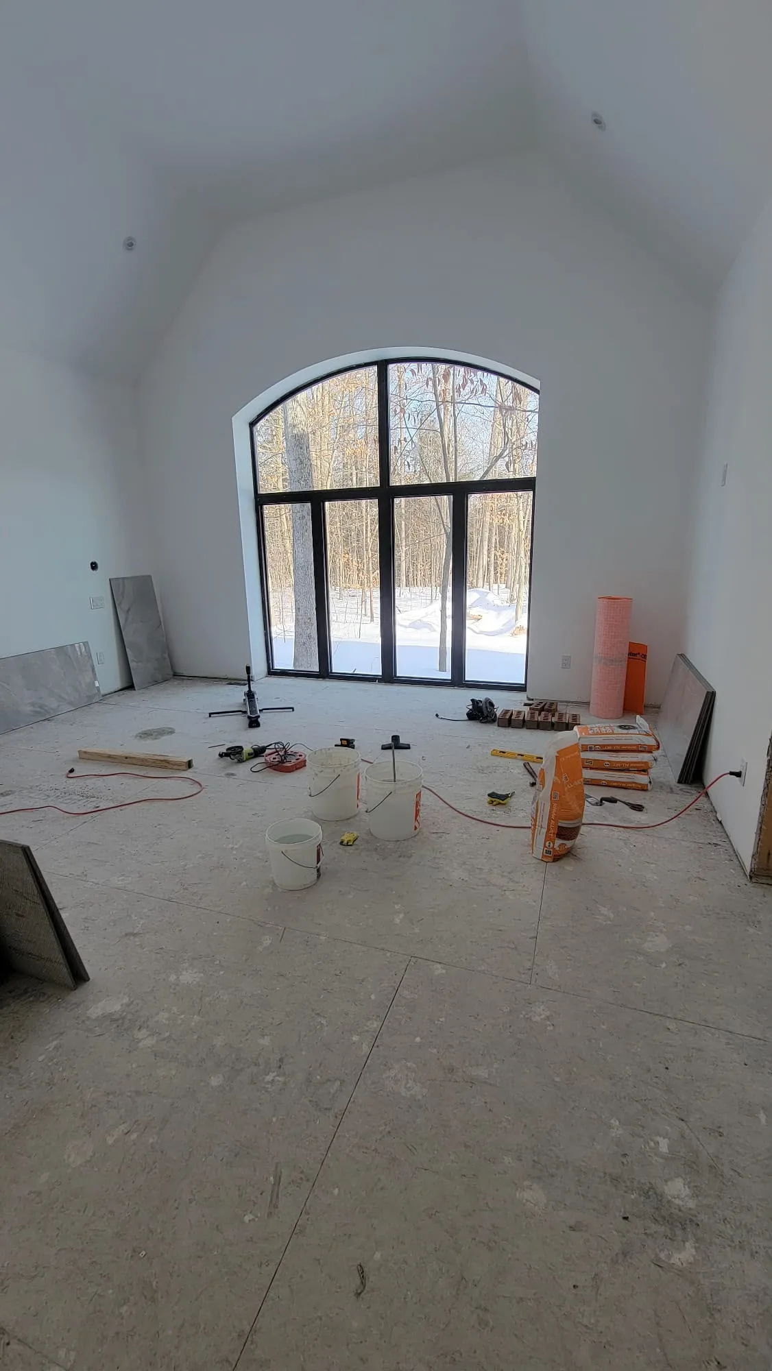 New build interior painting project in Ottawa — large room with vaulted ceiling and arched window under construction